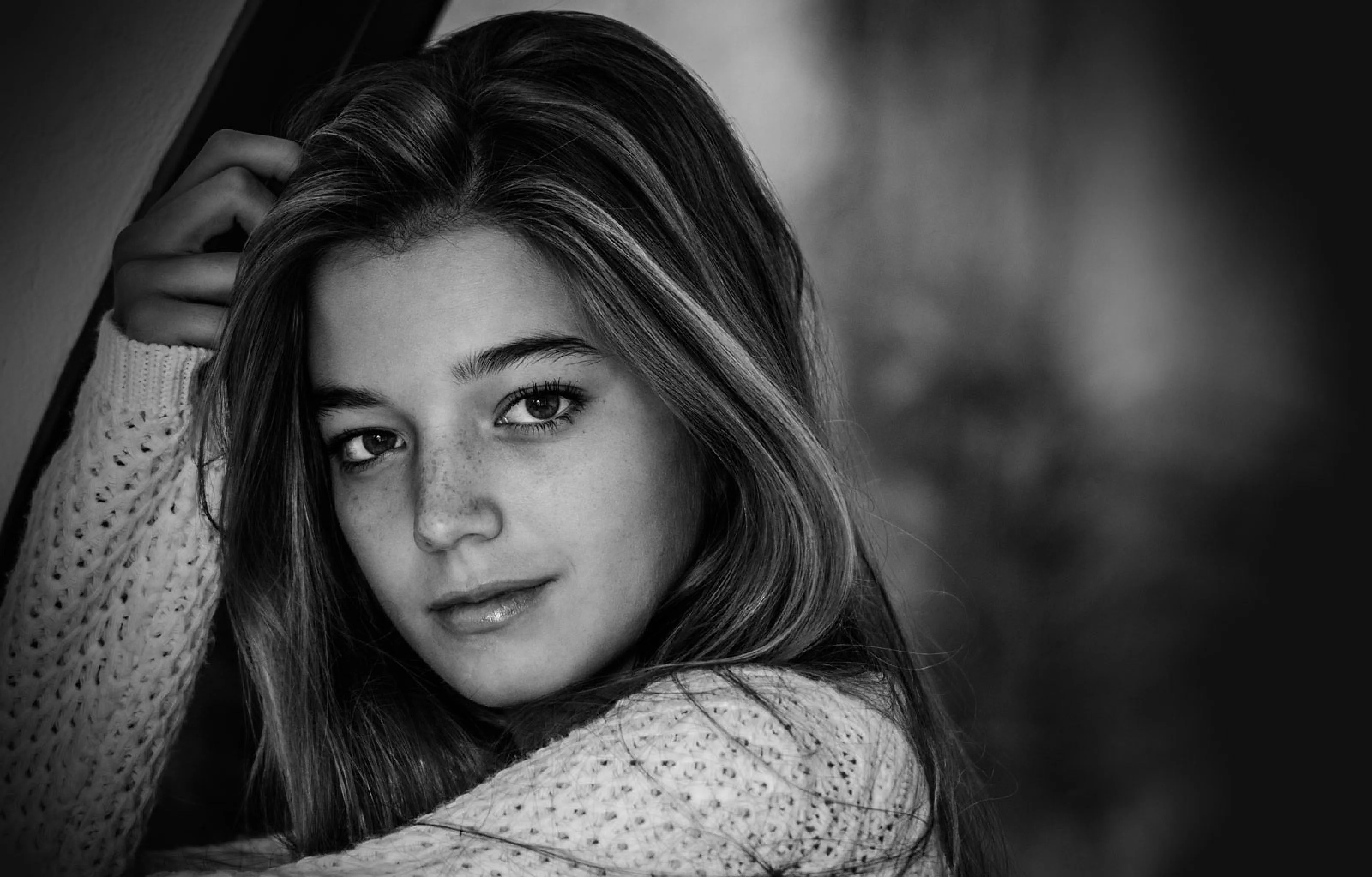 Black-and-white close portrait of a young woman in a knitted sweater